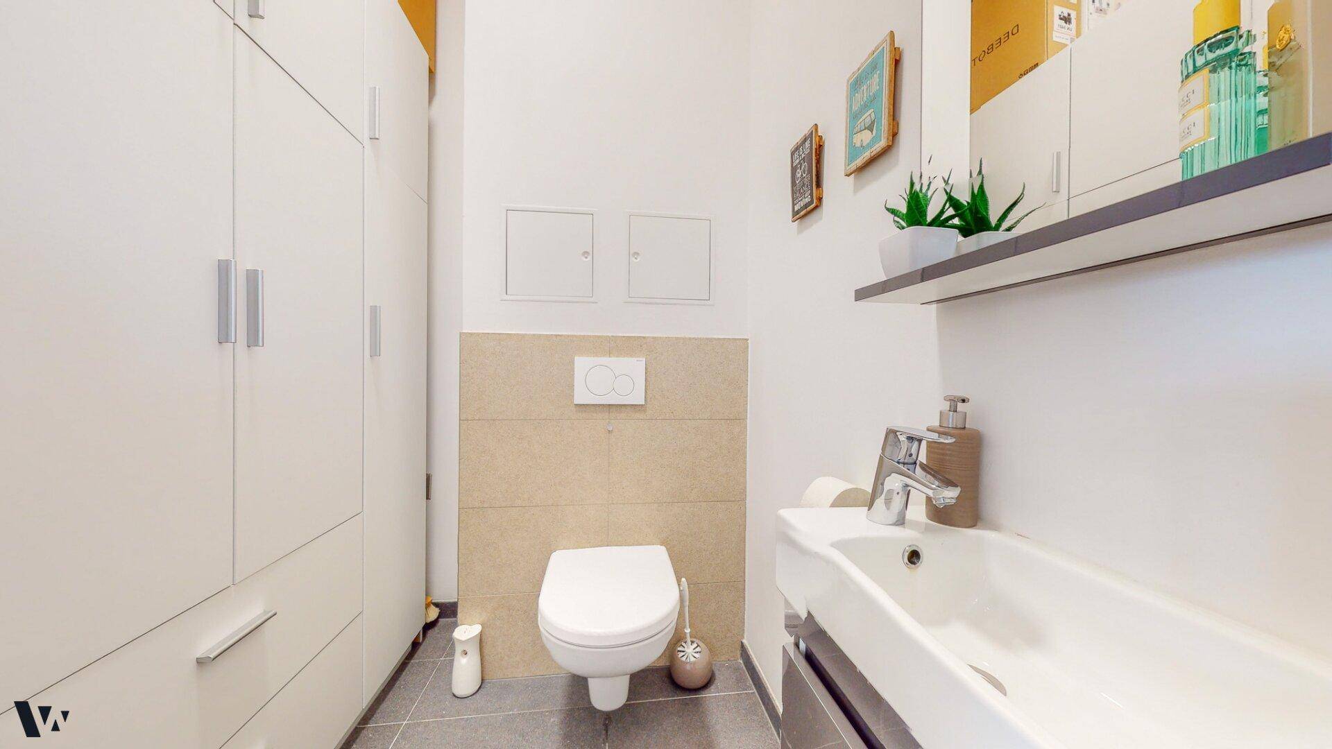 Modernes Gäste-WC mit wandhängender Toilette, Waschbecken und praktischen Einbauschränken.