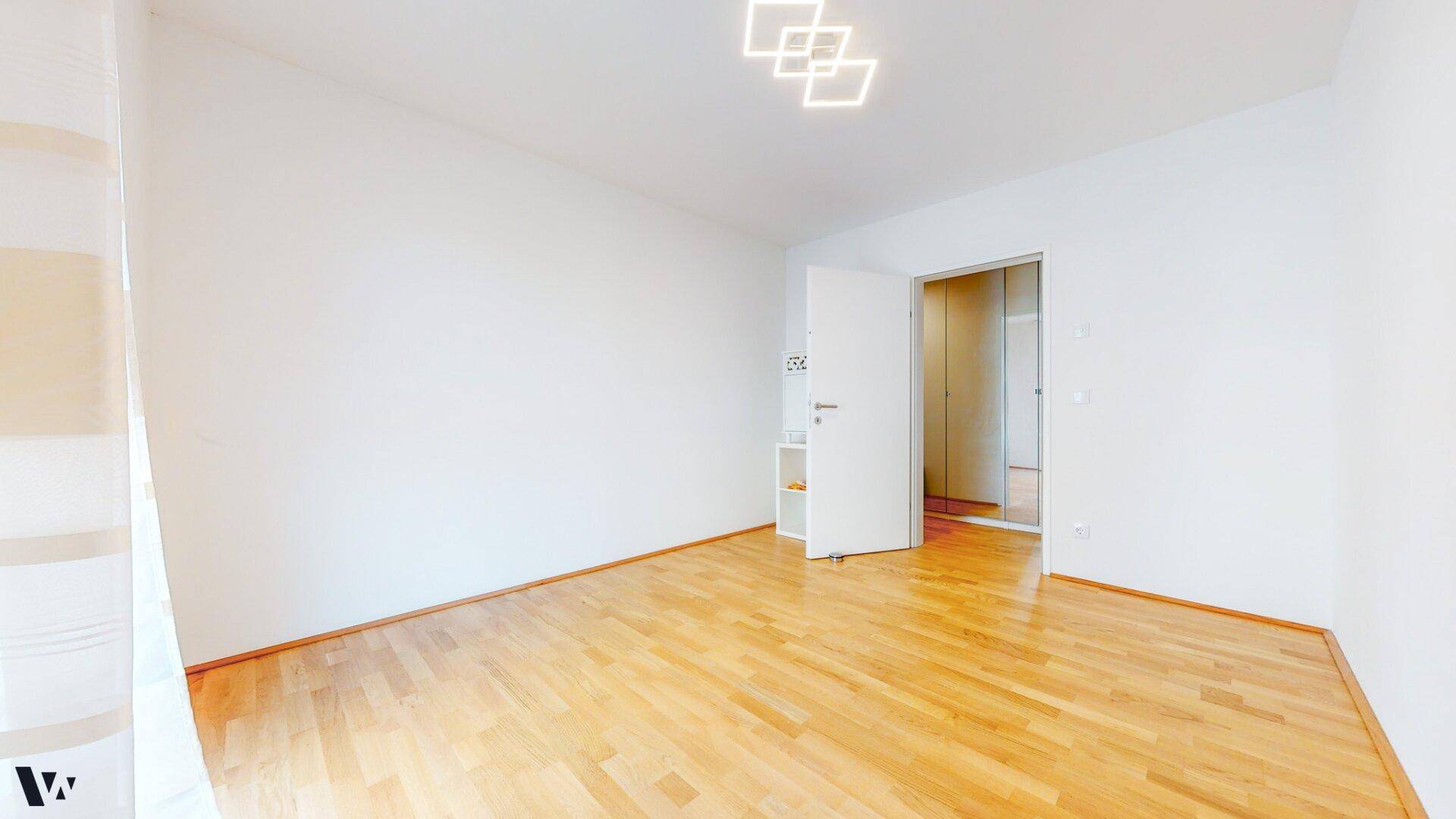 Leerer Raum mit hellem Holzfußboden und weißen Wänden, bereit zur individuellen Gestaltung.