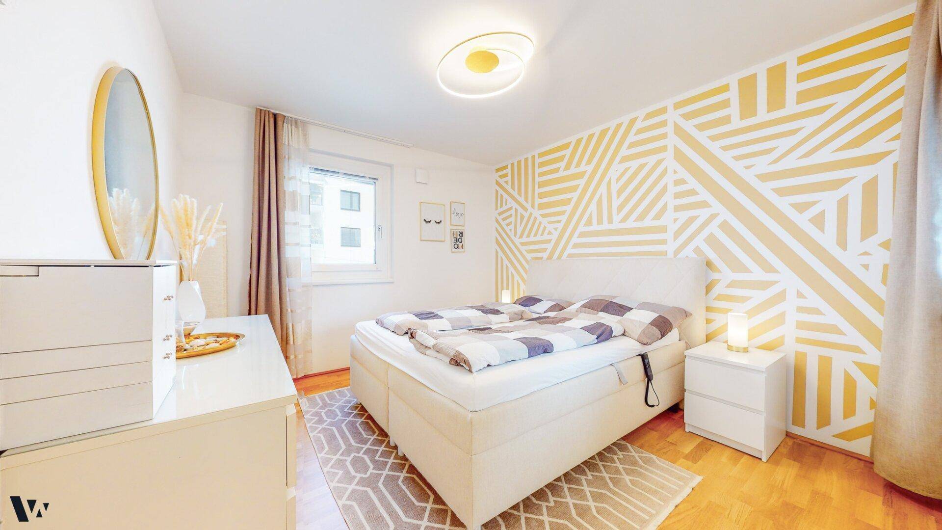 Gemütliches Schlafzimmer mit Doppelbett, modernem Muster an der Wand und Fenster.