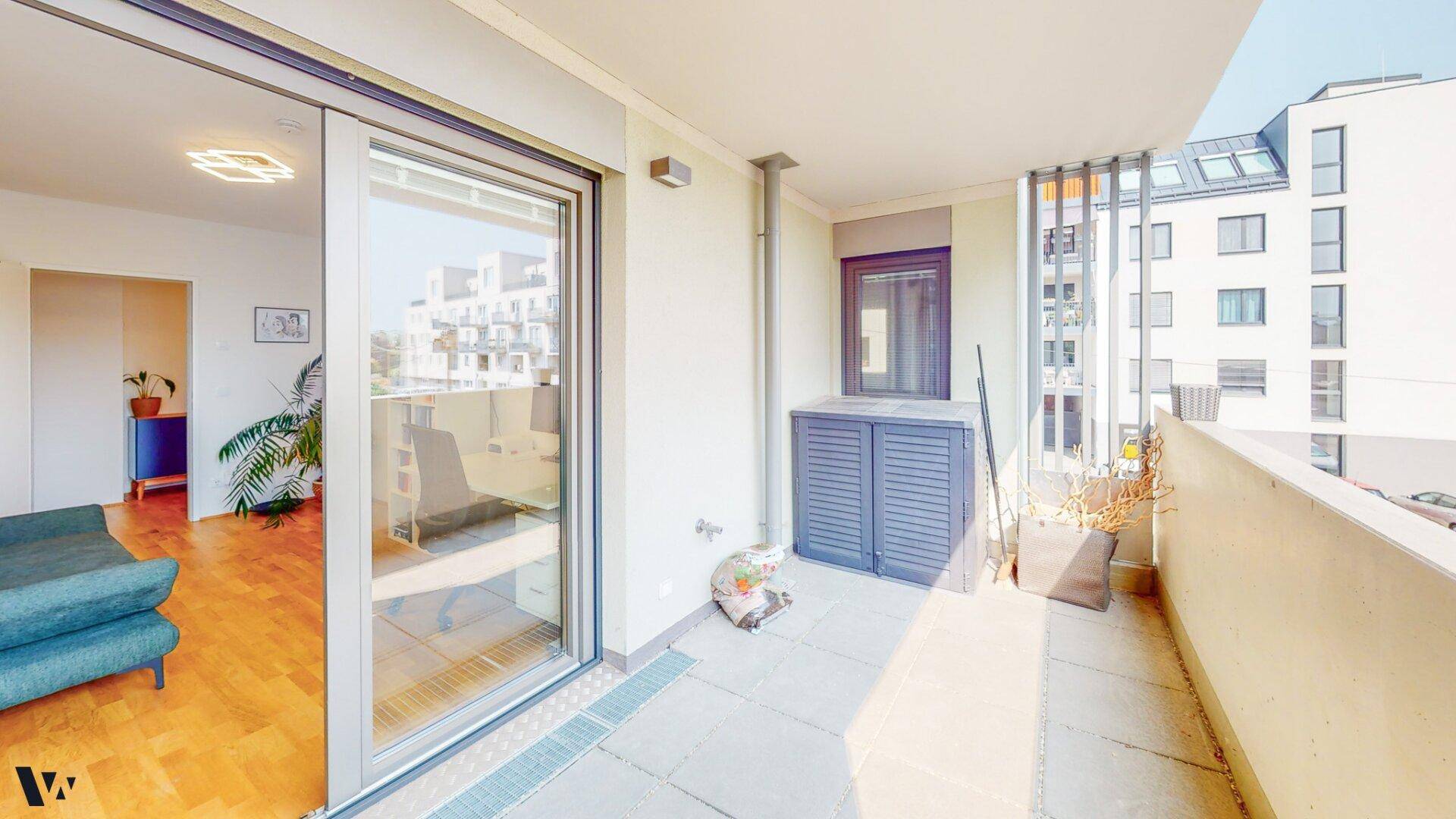 Sonniger Balkon mit Fliesenboden und praktischem Stauraum, zugänglich vom Innenbereich.