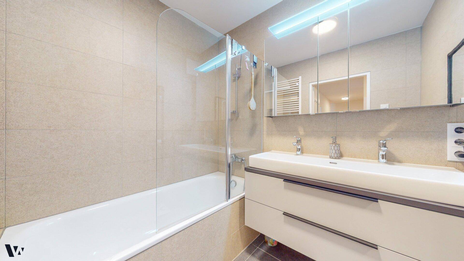 Modernes Badezimmer mit Badewanne, Doppelwaschbecken und großem Spiegelschrank.