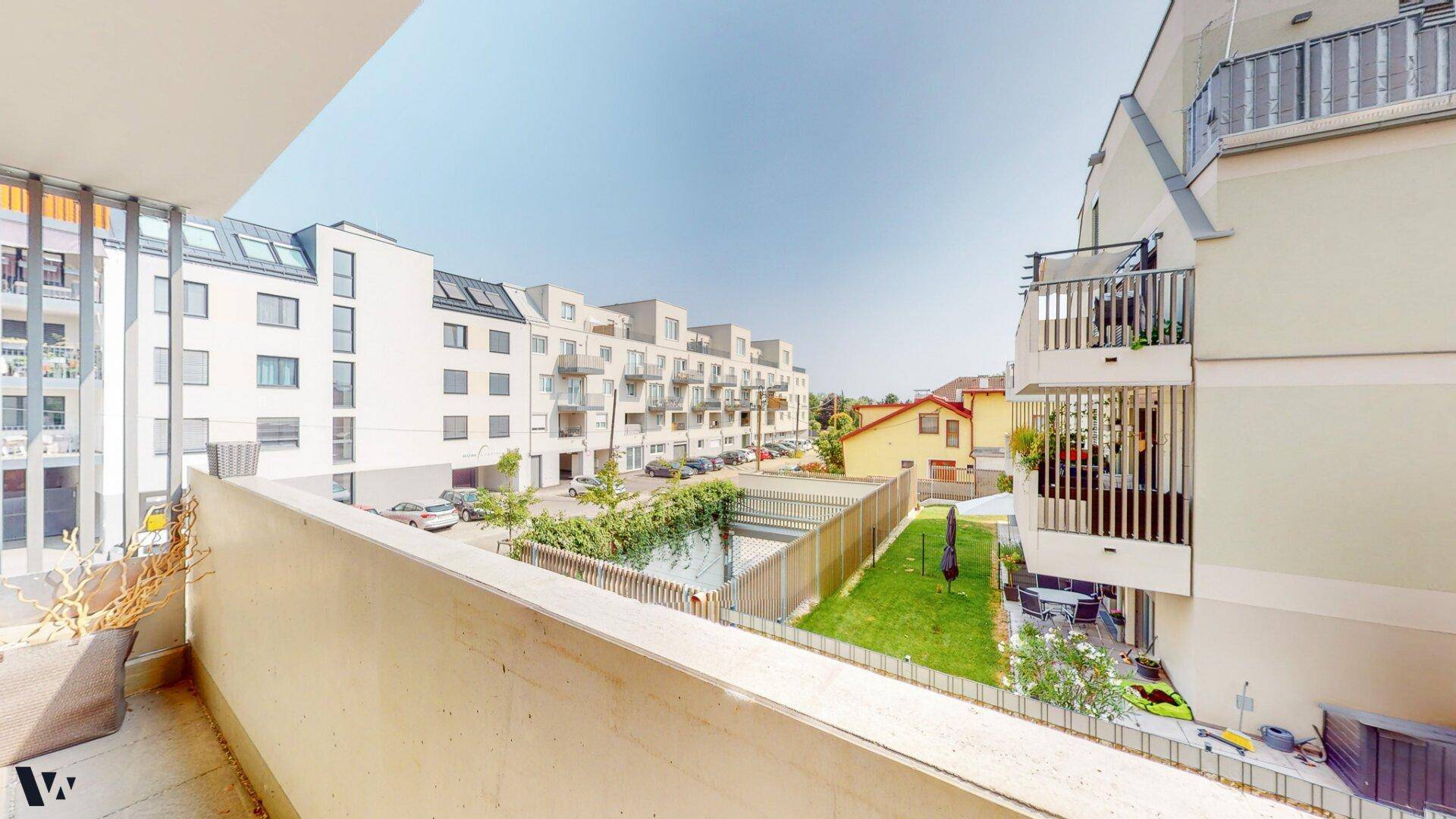 Weitläufiger Blick vom Balkon auf die Wohnanlage und eine grüne Fläche.