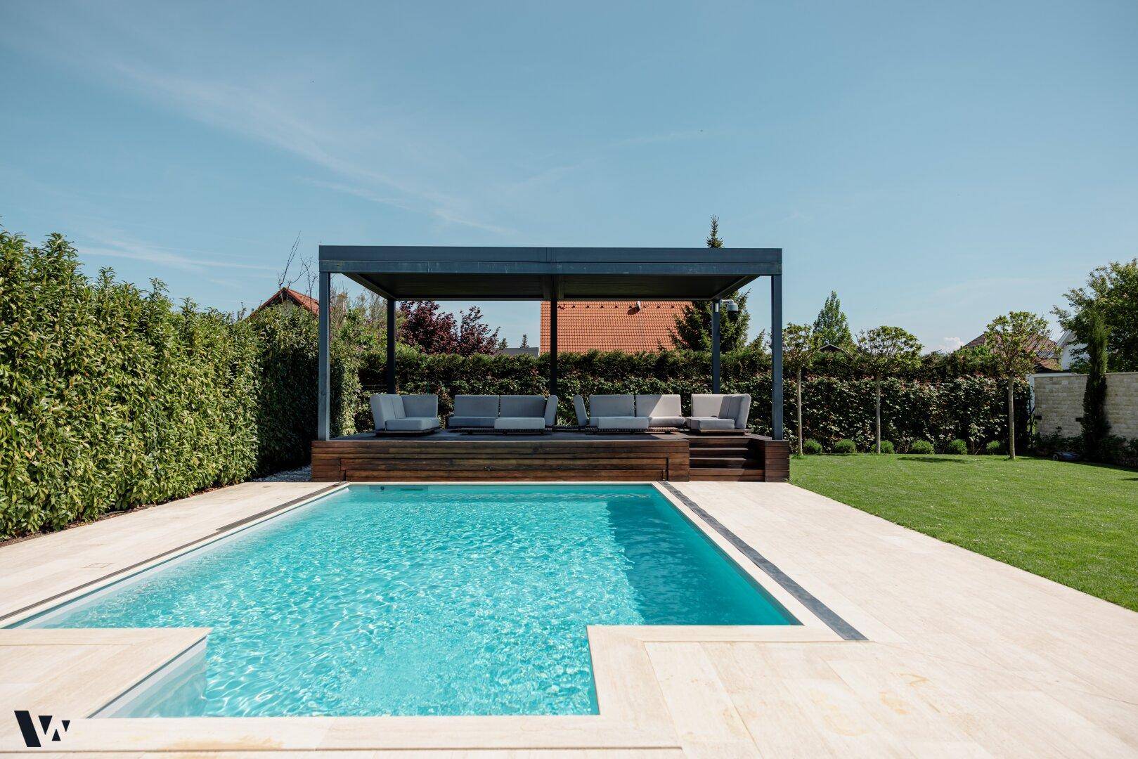 Entspannender Poolbereich mit überdachter Lounge-Zone und bequemen Gartenmöbeln im Grünen.