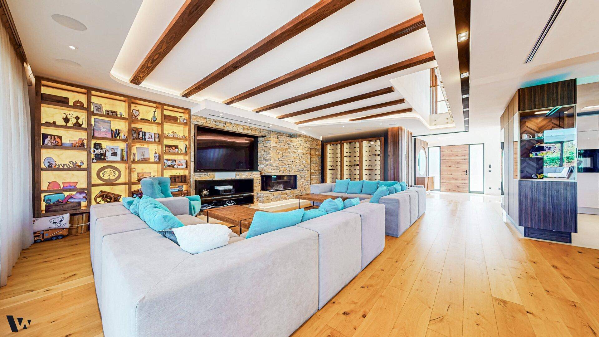 Elegantes Wohnzimmer mit Holzbalkendecke, Kamin und großzügiger Sitzlandschaft in modernem Design.