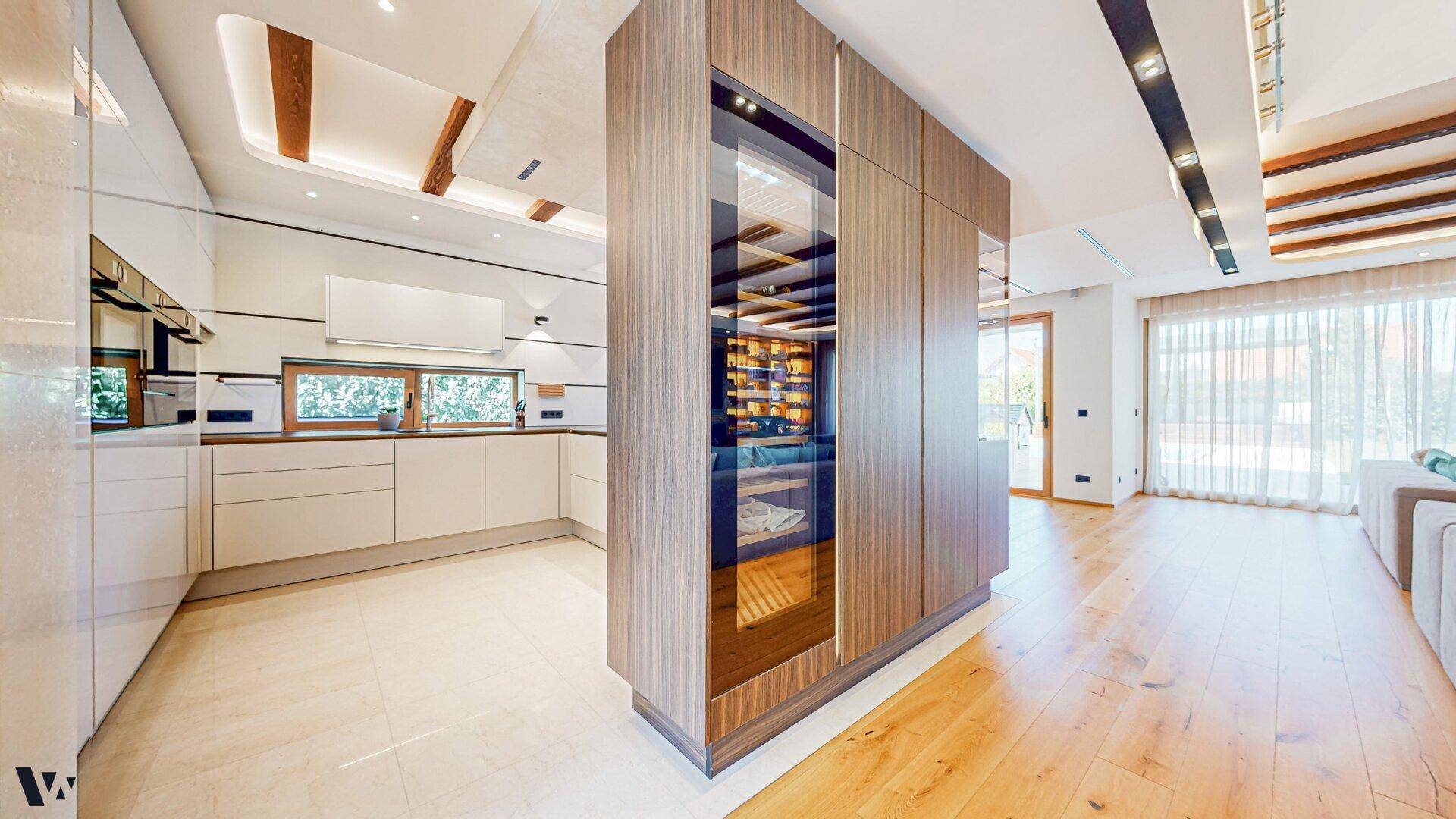 Moderne Küche mit weißen Schränken und integriertem Weinkühlschrank, verbunden mit dem Wohnbereich.