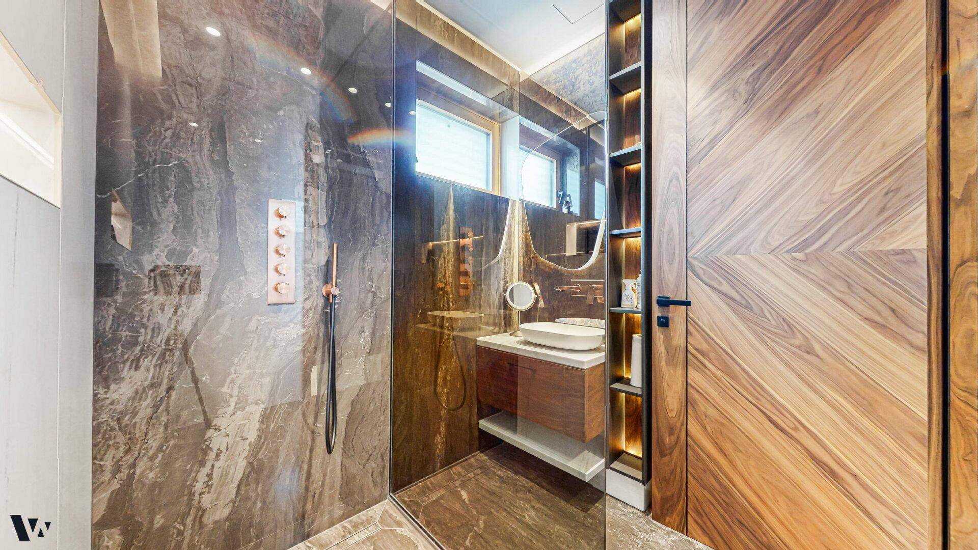 Luxuriöses Badezimmer mit großer begehbarer Dusche, Marmorwänden und Holzdetails.