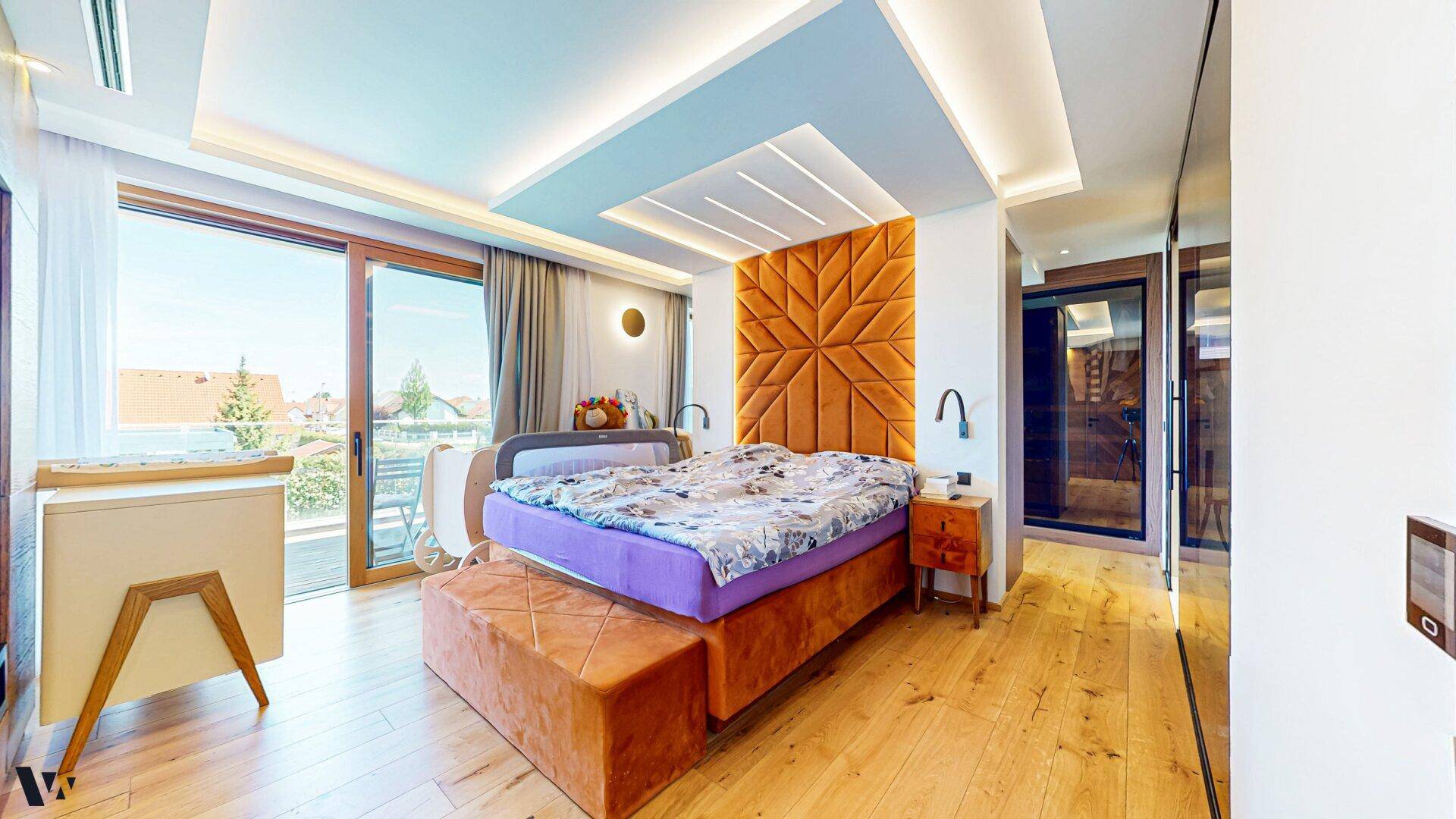 Modernes Schlafzimmer mit großem Bett, Holzboden und Zugang zu einem Balkon mit Aussicht.