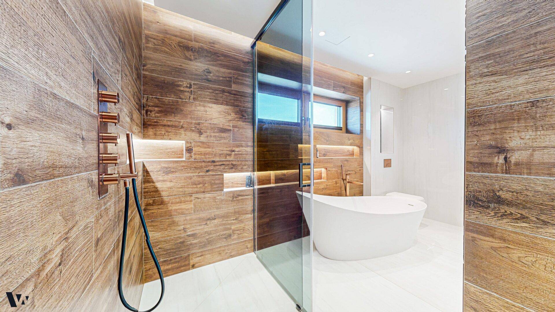 Geräumiges Badezimmer mit Holzverkleidung, freistehender Badewanne und großer Glasdusche.