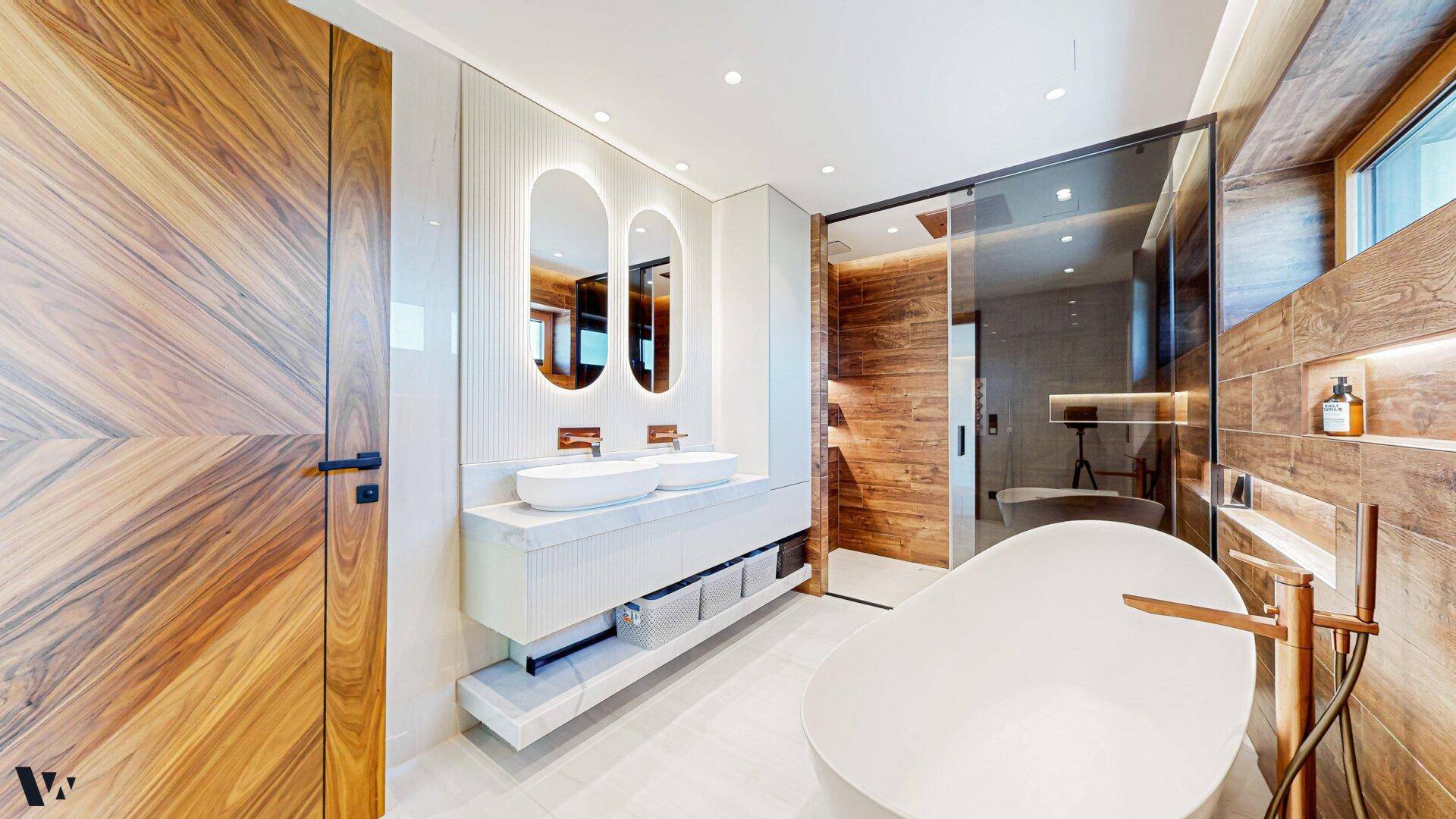 Elegantes Badezimmer mit Doppelwaschbecken, Holzdetails und moderner freistehender Badewanne.