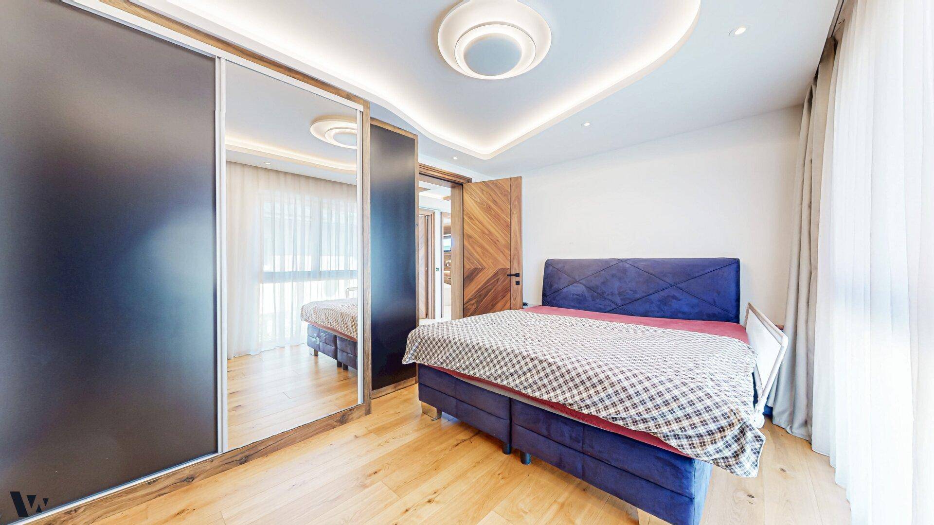 Gemütliches Schlafzimmer mit großem Bett, Spiegelschränken und Holzboden.