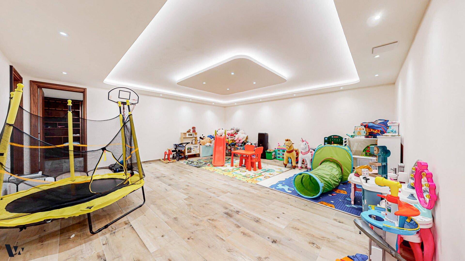 Großzügiger Spielraum mit Trampolin und vielfältigem Spielzeug für Kinder.