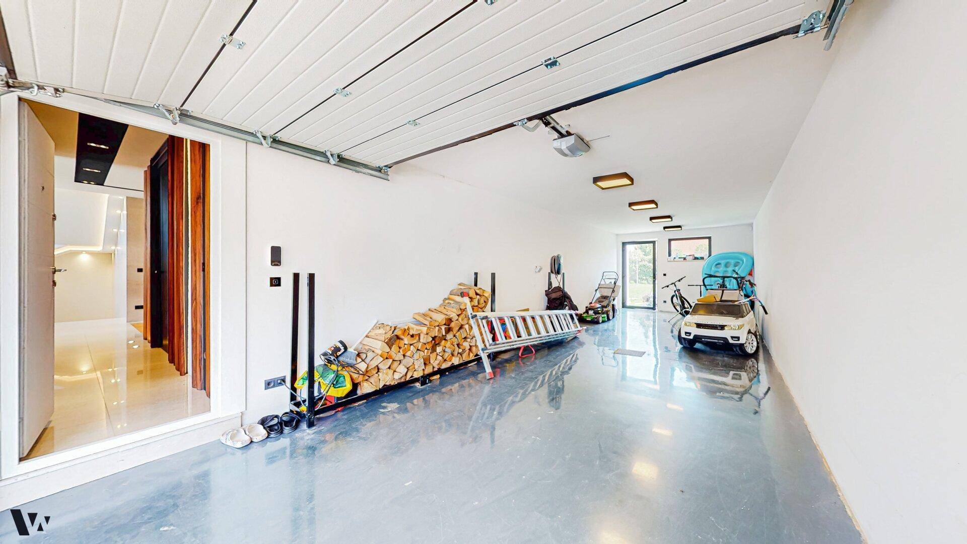 Geräumige Garage mit viel Stauraum, Holzstapel und Zugang zum Haus.