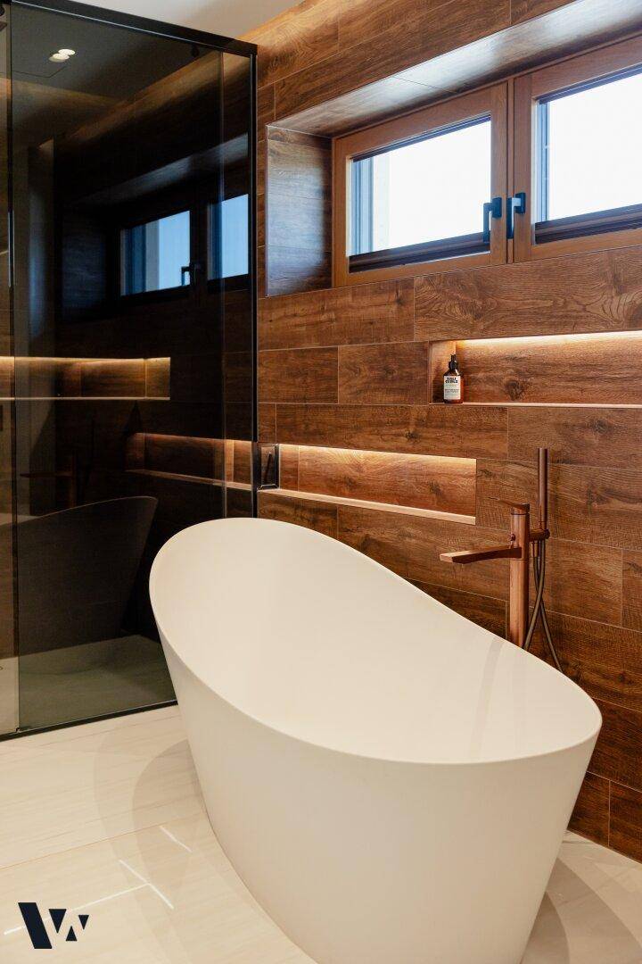 Modernes Badezimmer mit freistehender Badewanne, Holzverkleidung und integrierter Dusche.