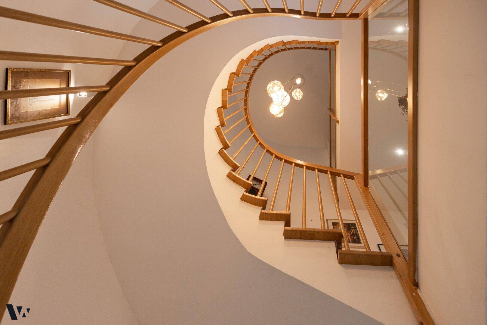 Elegante Wendeltreppe aus Holz mit filigranem Geländer, die die Etagen verbindet.