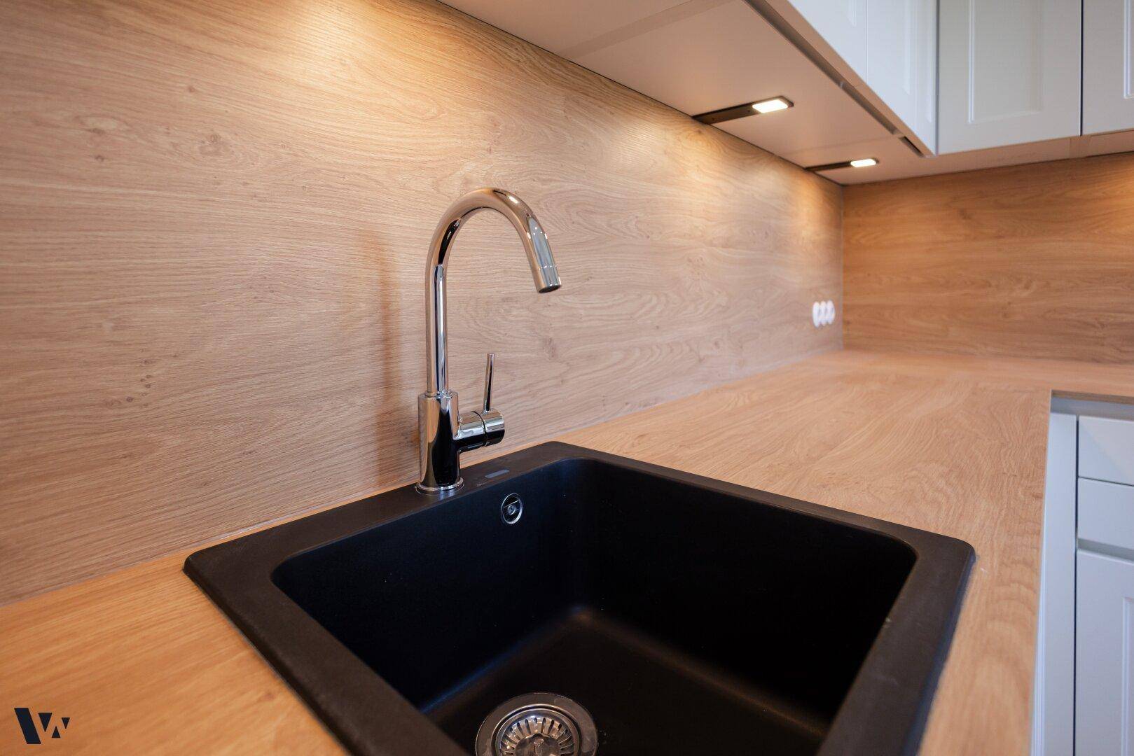 Detailaufnahme der modernen schwarzen Spüle mit Chromarmatur und Holz-Arbeitsplatte.