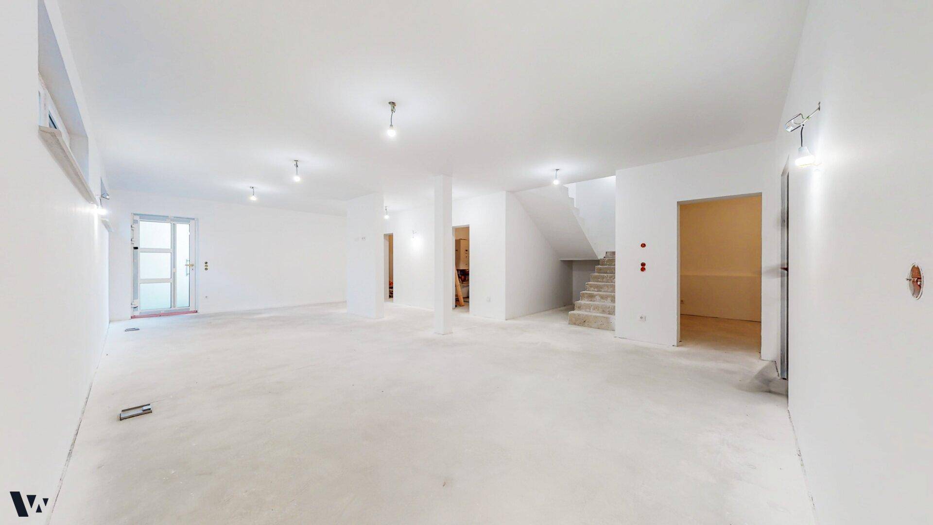 Großer, heller Raum im Rohbau mit Säulen und vorbereiteten Installationen im Untergeschoss.