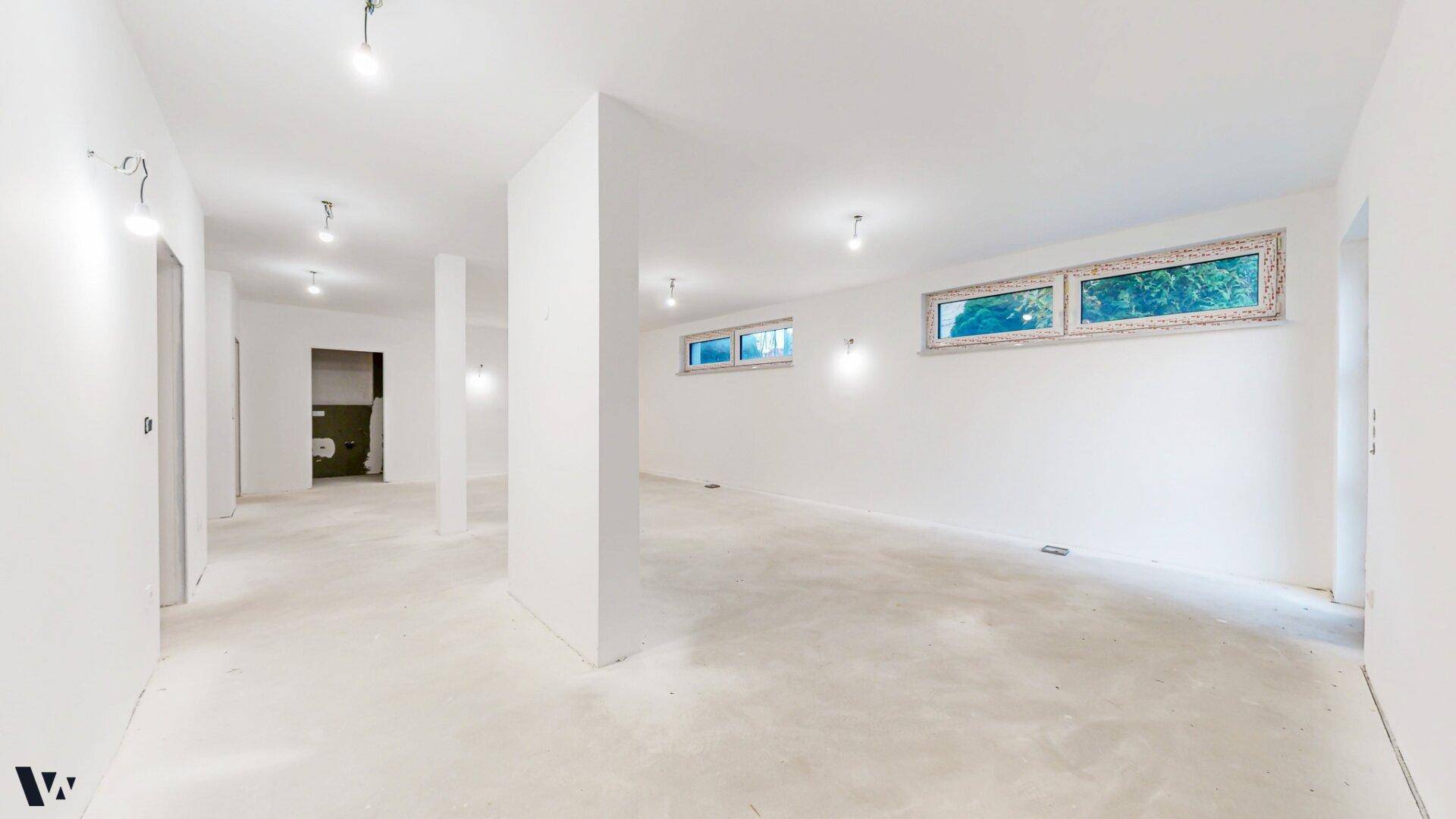 Heller Kellerraum im Rohbau mit mehreren Fenstern und viel Tageslicht für zukünftige Nutzung.