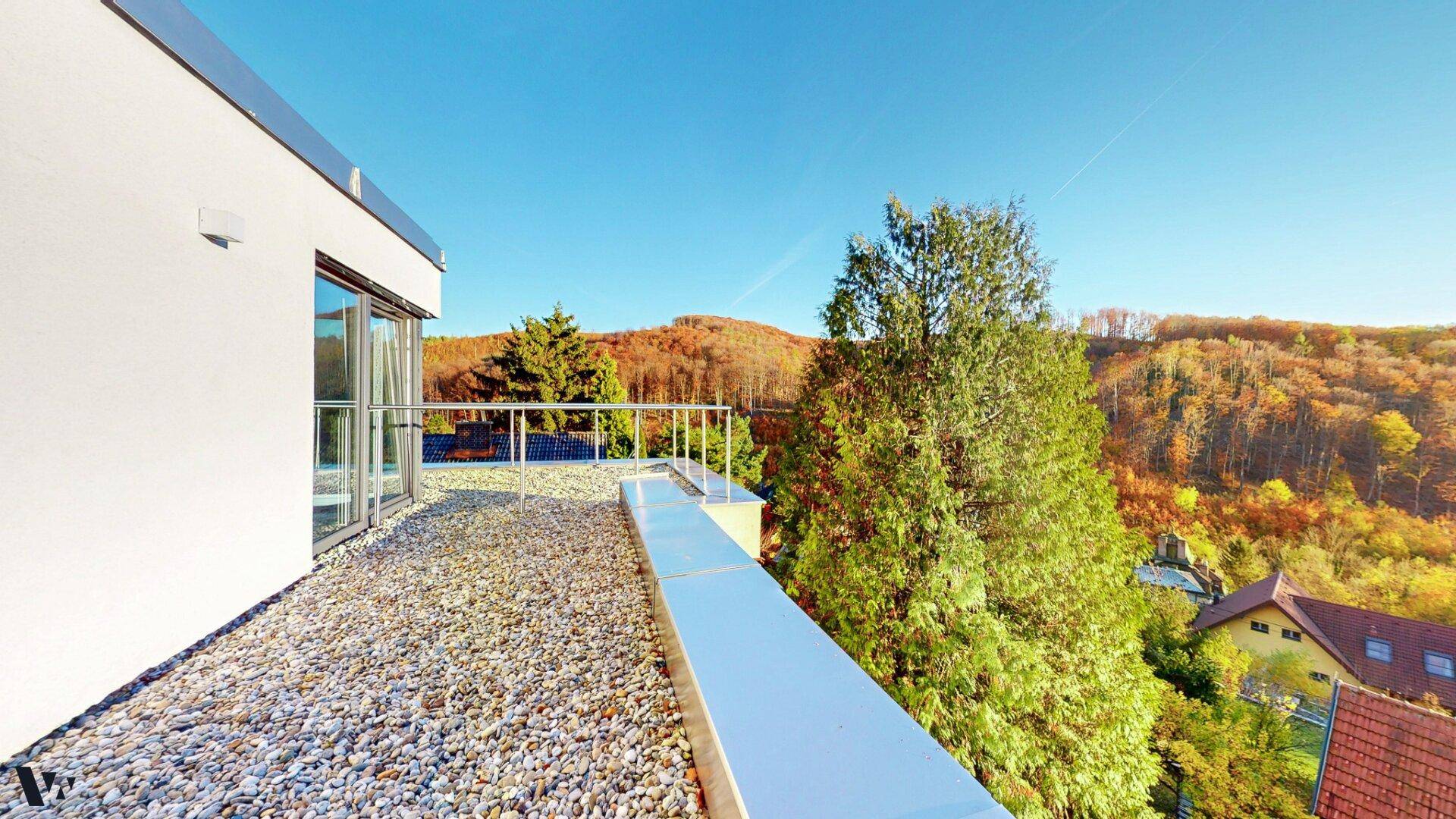 Geräumige Dachterrasse mit Kiesbelag und weitem Blick auf die bewaldeten Hügel und das Tal.