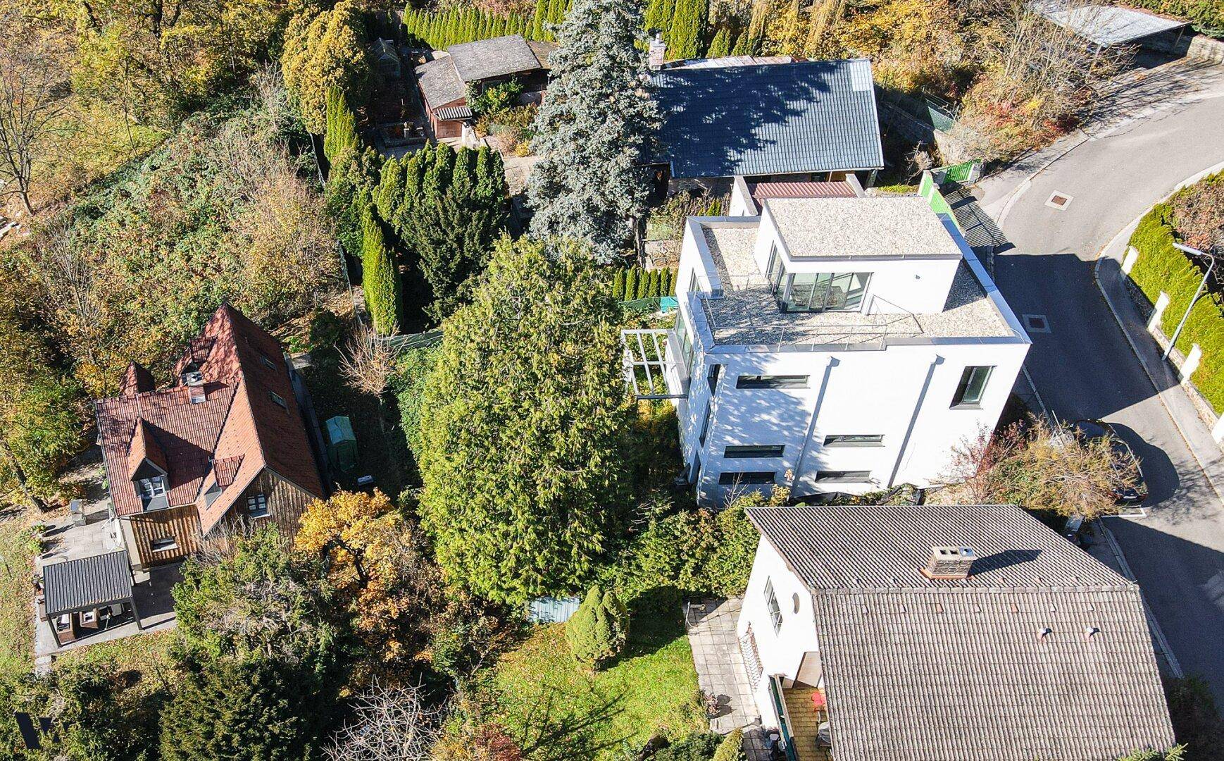 Vogelperspektive des modernen Hauses mit Dachterrasse und weitem Blick auf die bewaldete Umgebung.