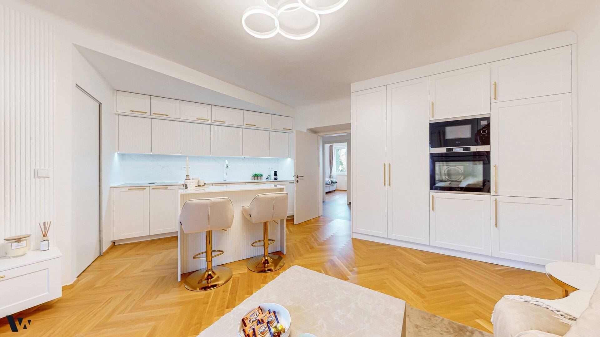 Moderne weiße Einbauküche mit integrierten Geräten, Kochinsel und Parkettboden.