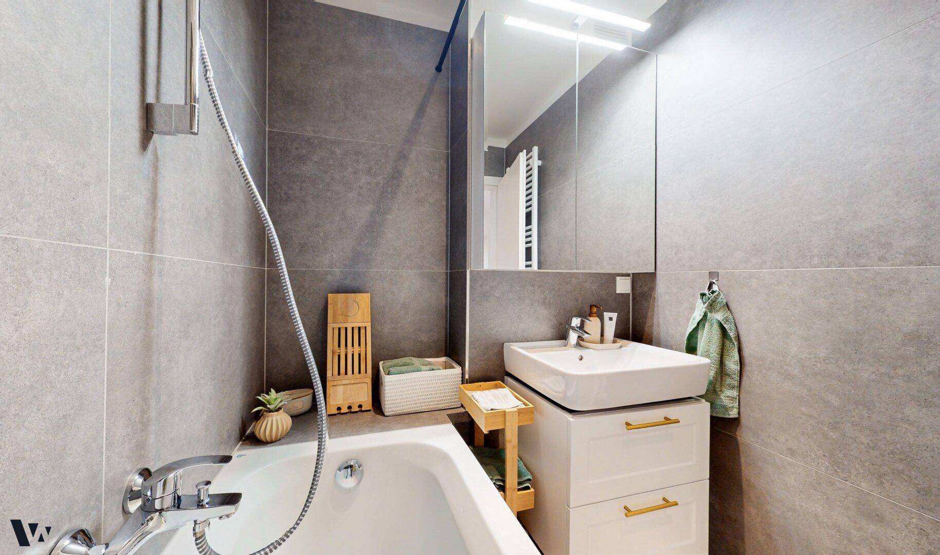 Detailansicht des Badezimmers mit Badewanne, Waschtisch und Spiegelschrank.