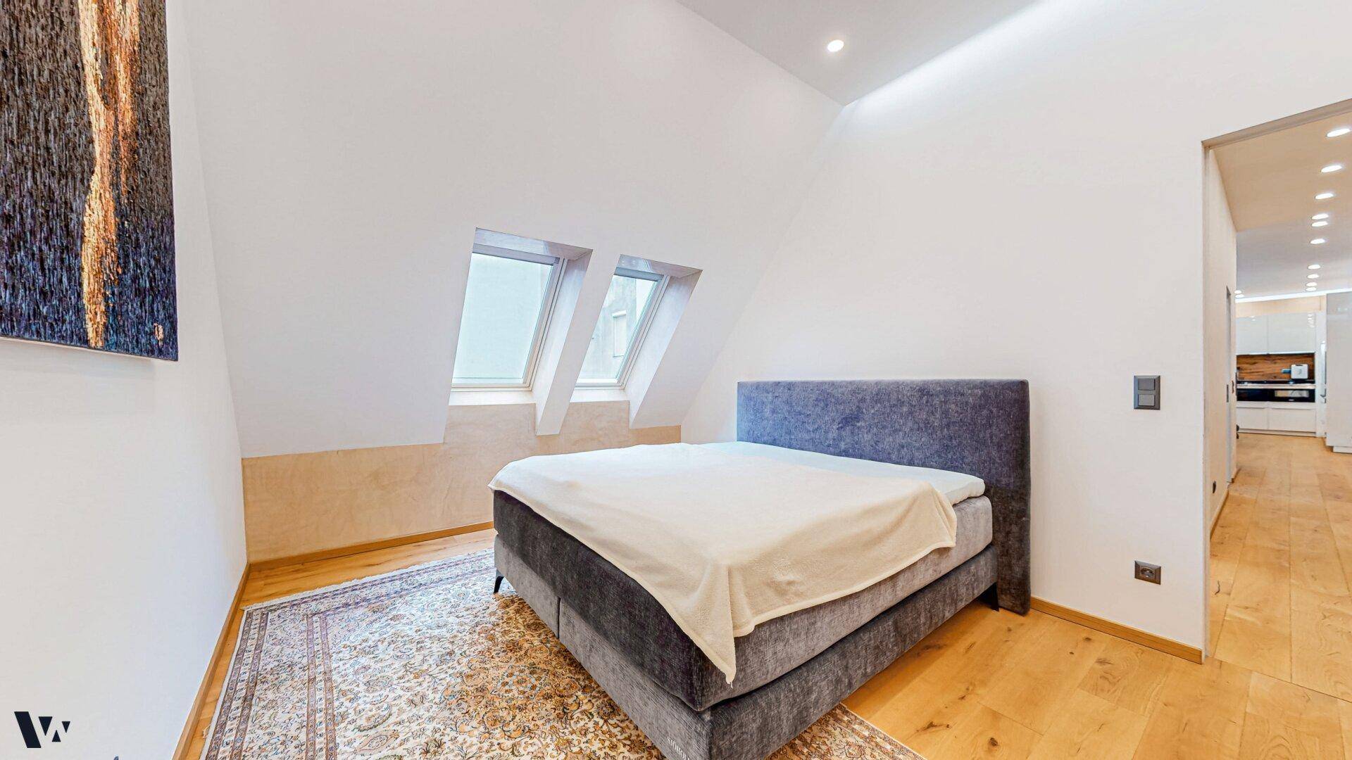 Gemütliches Schlafzimmer mit Holzboden, großem Bett und natürlichem Licht durch Dachfenster.