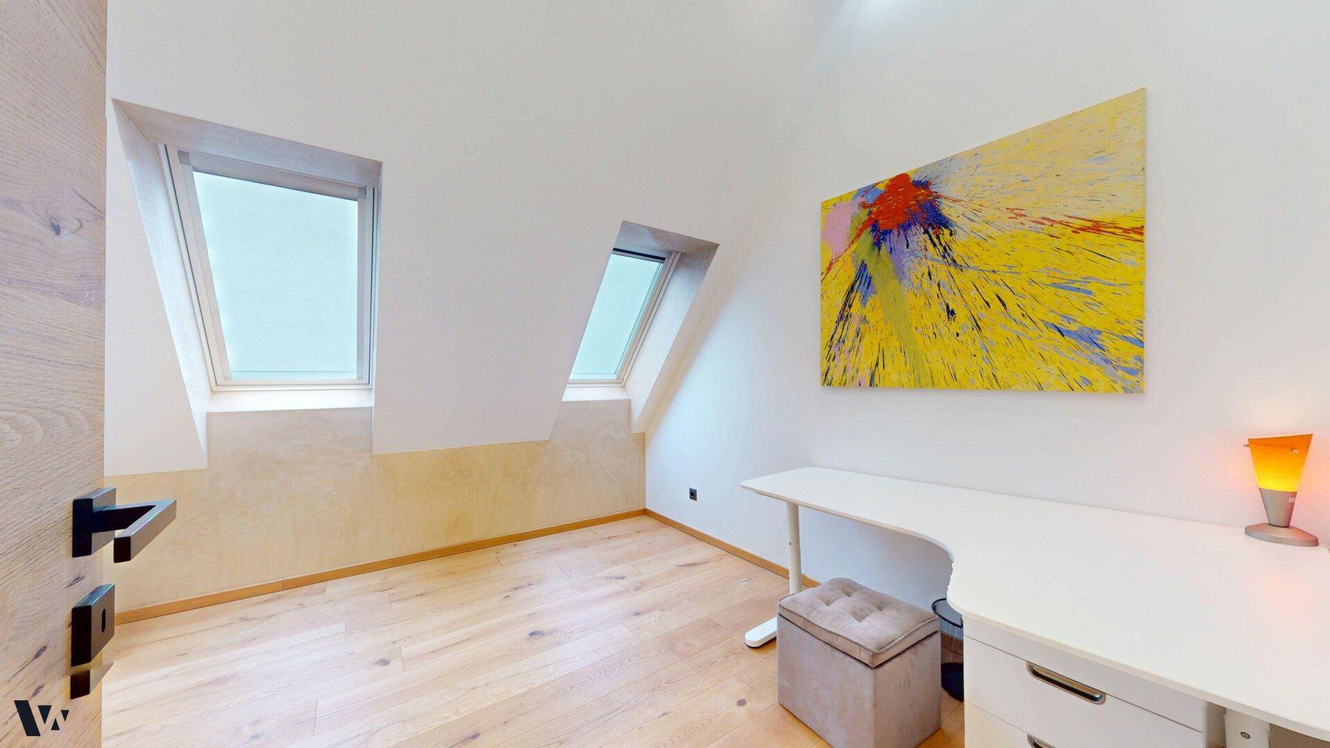 Helles Arbeitszimmer mit Schreibtisch, Holzboden und natürlichem Licht durch Dachfenster.