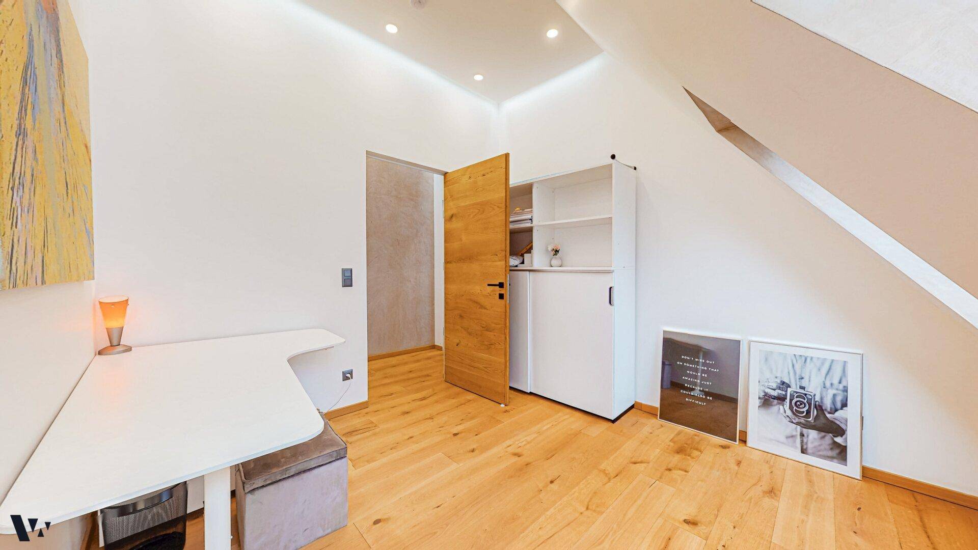 Funktionales Arbeitszimmer mit Schreibtisch, Stauraum und hellem Holzboden.