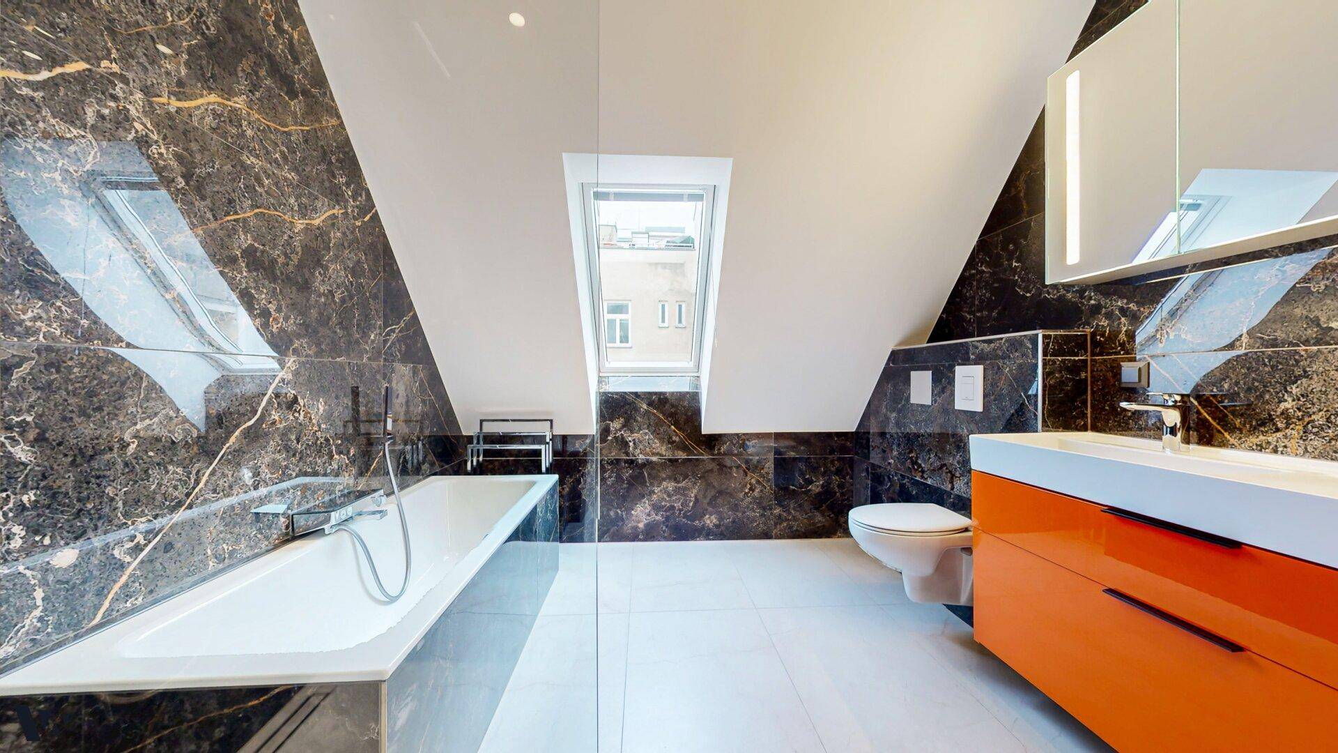 Elegantes Badezimmer mit dunklen Marmorfliesen, Badewanne und einem Dachfenster.