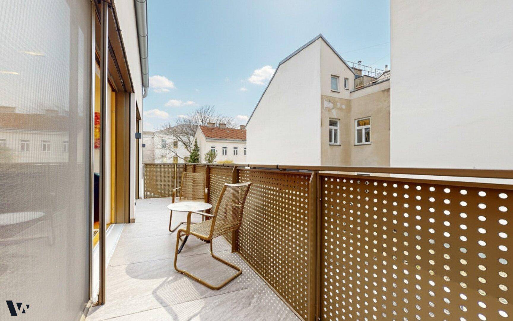 Sonniger Balkon mit Sitzgelegenheiten und Blick auf die umliegenden Gebäude der Stadt.