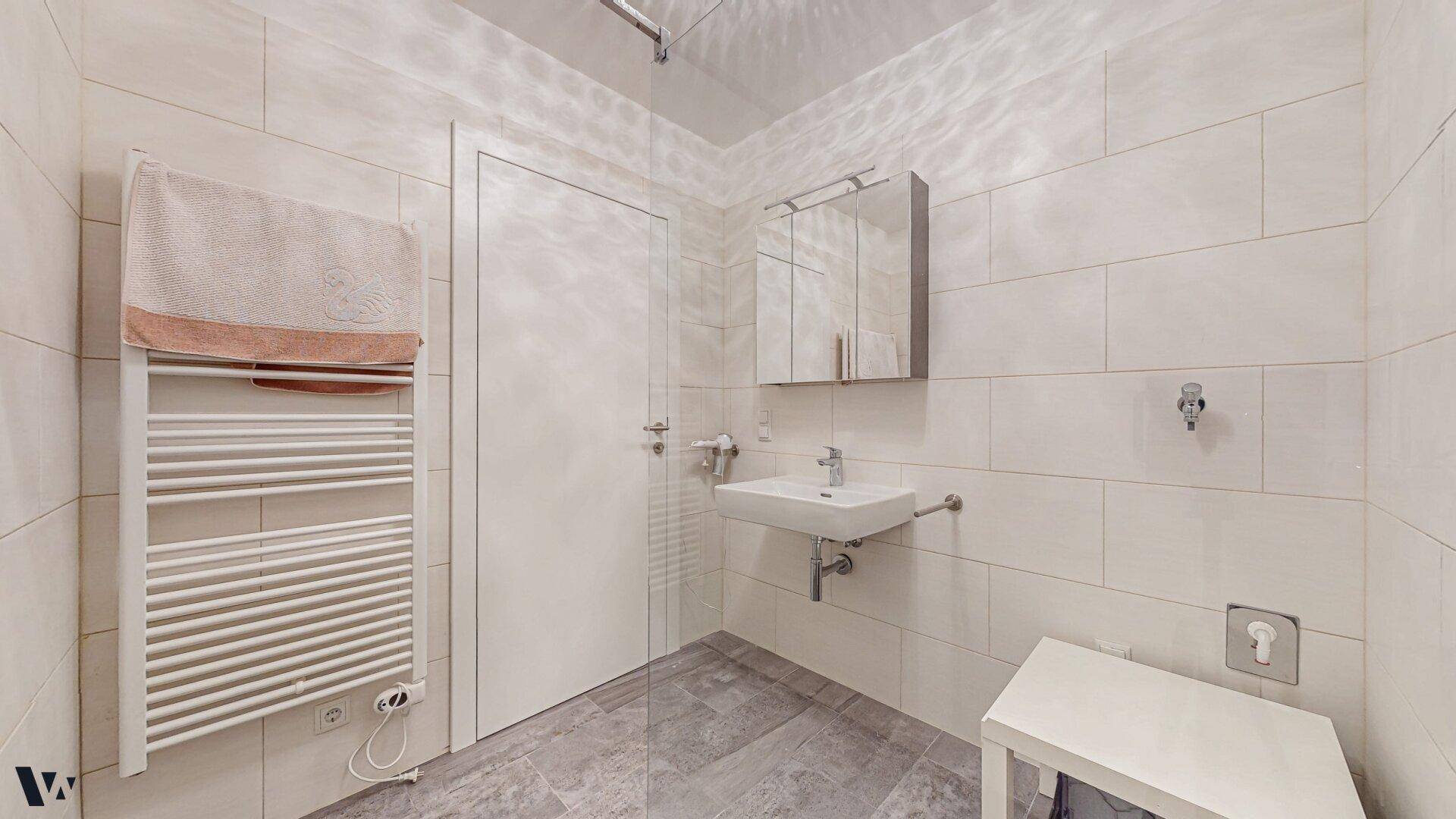Helles Badezimmer mit weiß gefliesten Wänden, beheiztem Handtuchhalter und moderner Ausstattung.