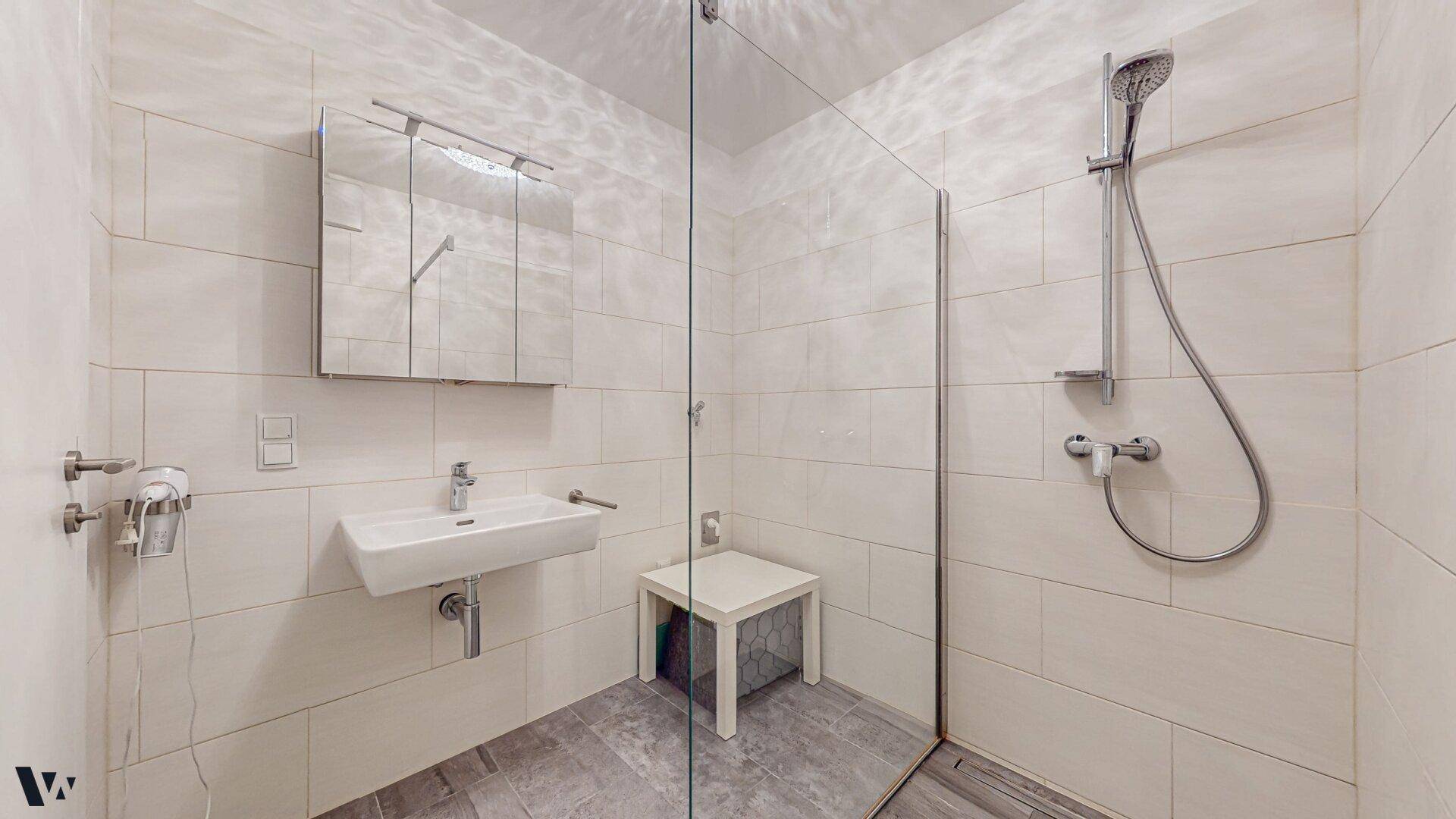 Modernes Badezimmer mit ebenerdiger Dusche, Wandwaschbecken und Spiegelschrank.
