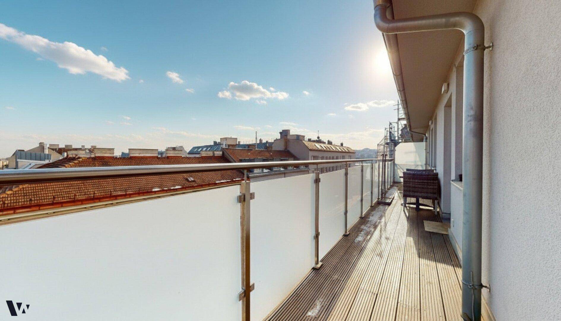 Sonniger Balkon mit Holzdielen und modernem Glasgeländer, ideal für entspannte Stunden im Freien.