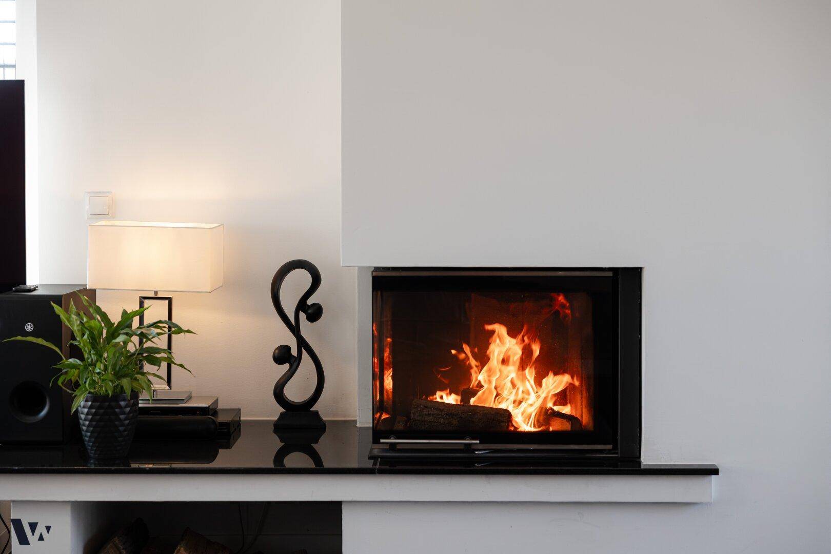 Moderner Einbaukamin mit brennendem Feuer, umgeben von minimalistischer Dekoration.