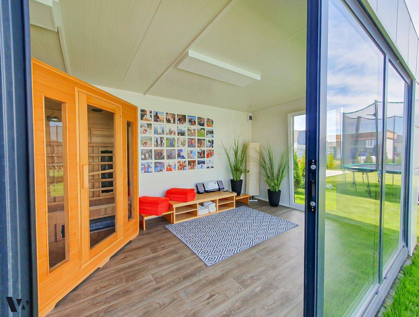 Entspannungsbereich mit einer modernen Holzsauna und großen Glasfronten zum Garten.