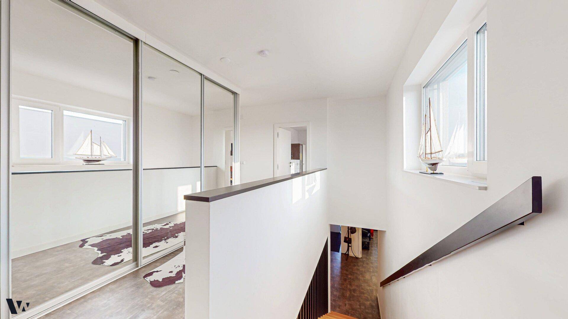 Heller Flur im Obergeschoss mit Spiegelschränken und Blick nach draußen durch die Fenster.