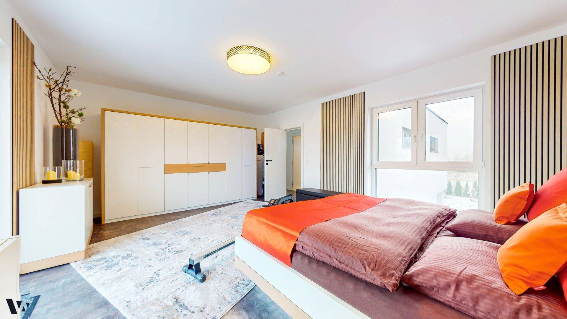 Helles Schlafzimmer mit großen Einbauschränken, Doppelbett und Fenster mit Ausblick.