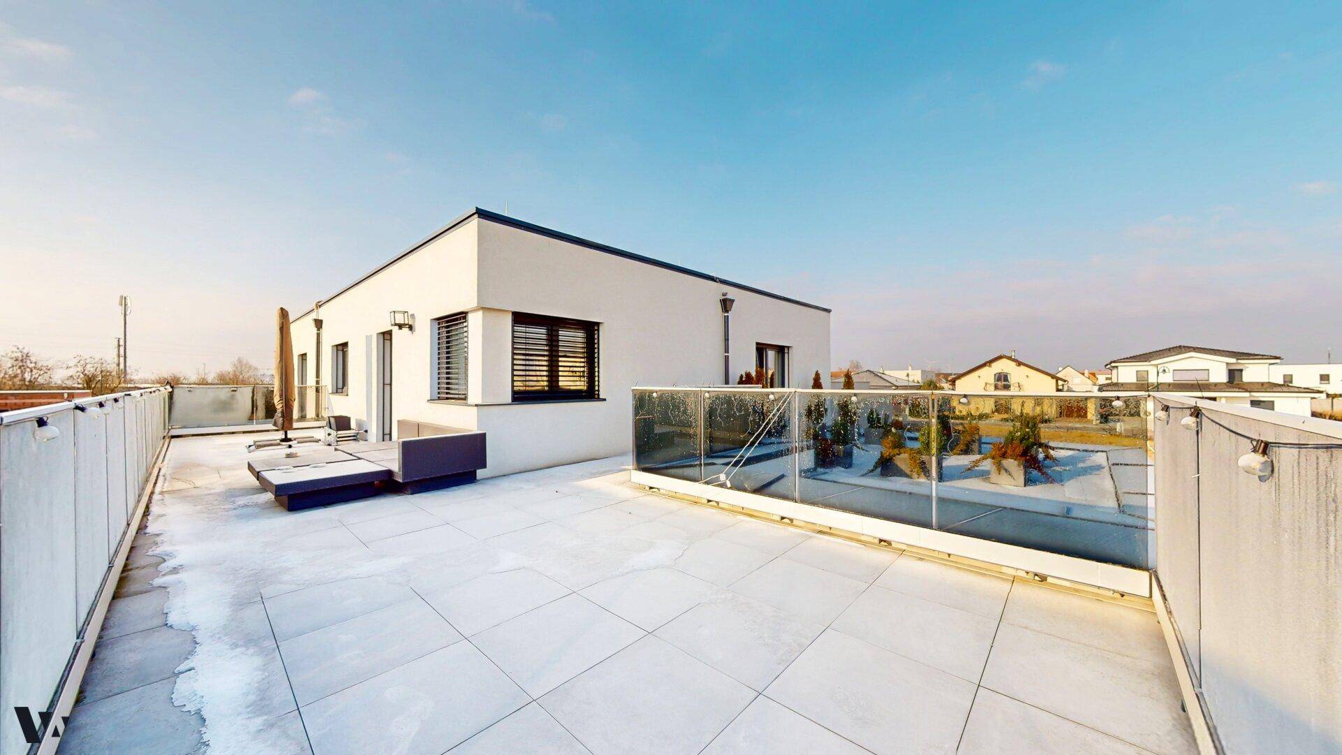 Weitläufige Dachterrasse mit Glasgeländer und Panoramablick über die Umgebung.