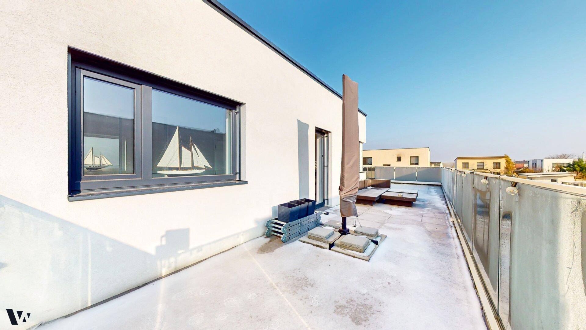 Sonnige Dachterrasse mit viel Platz und einem Sonnenschirm, ideal zum Entspannen.