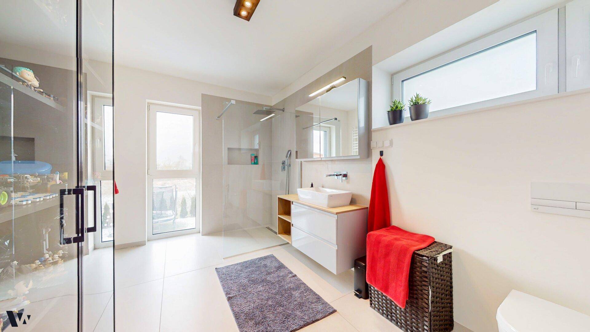 Modernes Badezimmer mit begehbarer Dusche, Einzelwaschbecken und großen Fliesen.