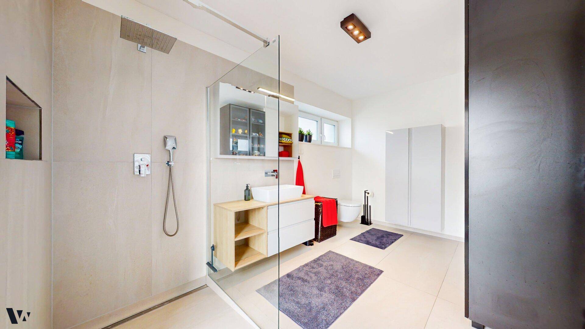 Helles Badezimmer mit großer begehbarer Dusche, modernem Waschbecken und Fenster.