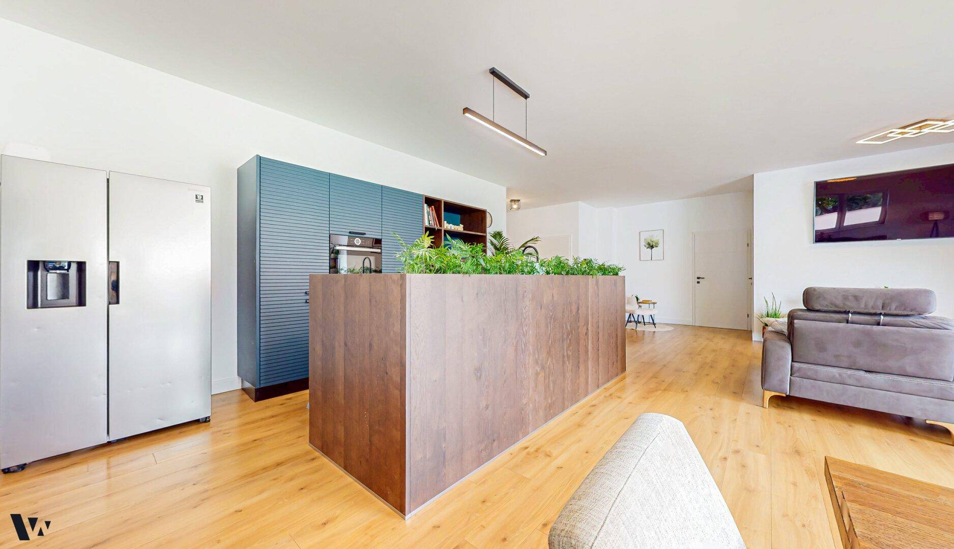 Moderne Einbauküche mit blauen Schränken, Kücheninsel und integriertem Kühlschrank.