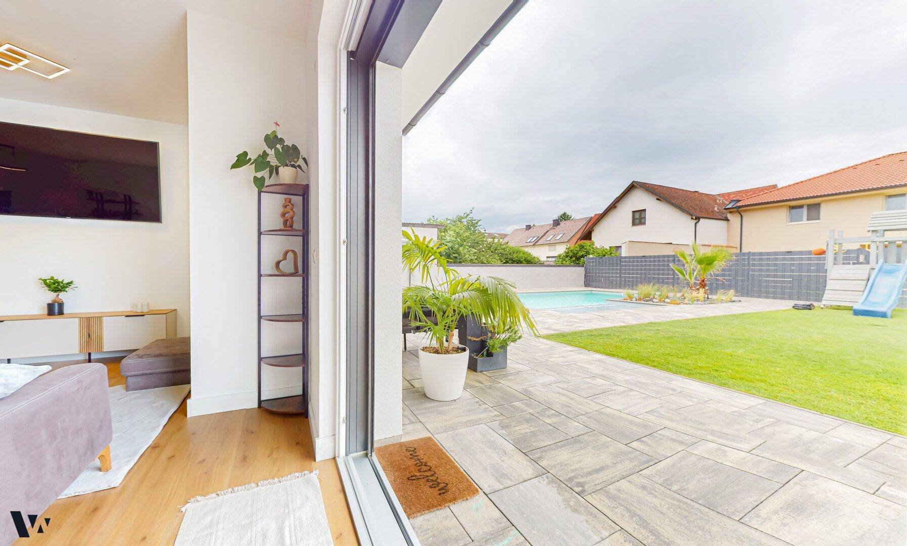 Heller Wohnbereich mit Holzboden und direktem Zugang zur Terrasse und zum Poolbereich.