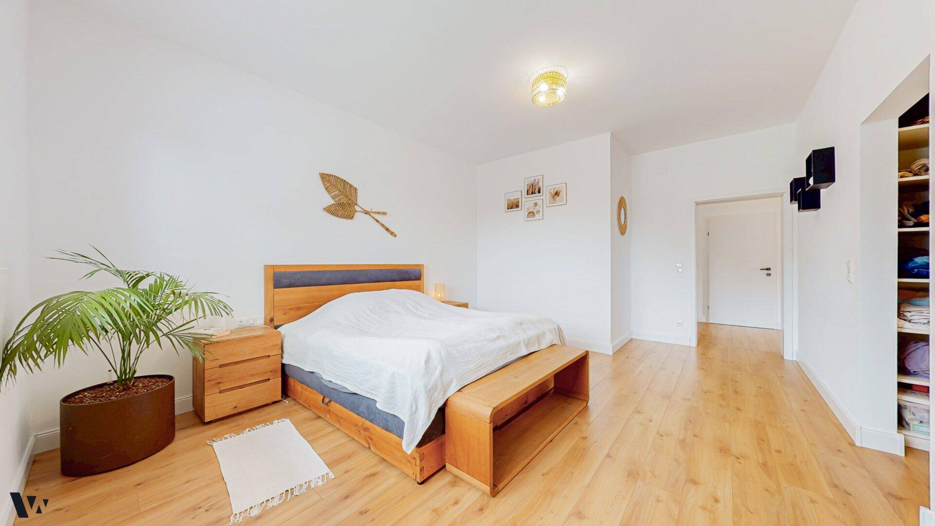 Geräumiges Schlafzimmer mit Holzboden, Holzbett und integriertem Stauraum.