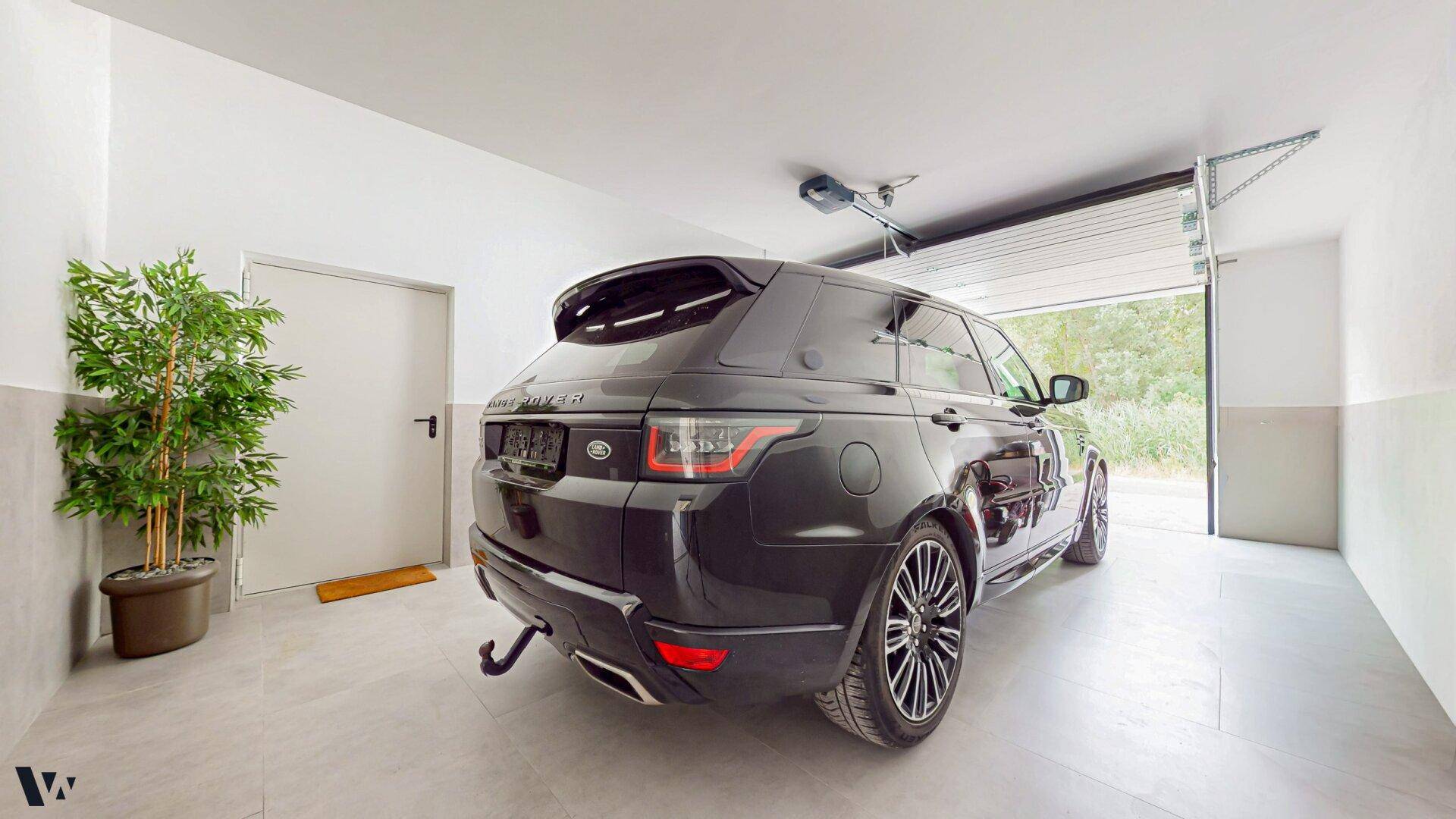 Geräumige Garage mit Fliesenboden und automatischem Garagentor, Platz für ein Fahrzeug.