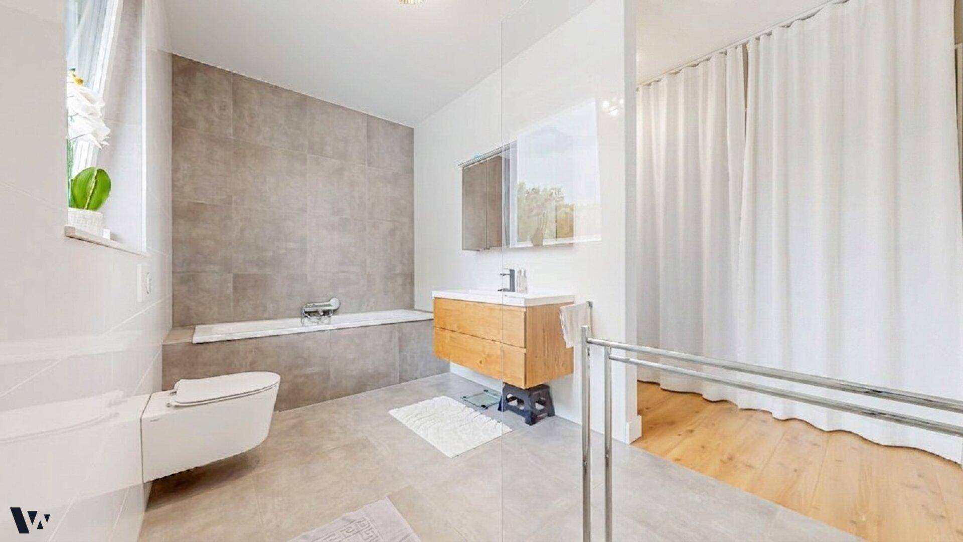 Modernes Badezimmer mit Badewanne, Waschtisch und großformatigen Fliesen.