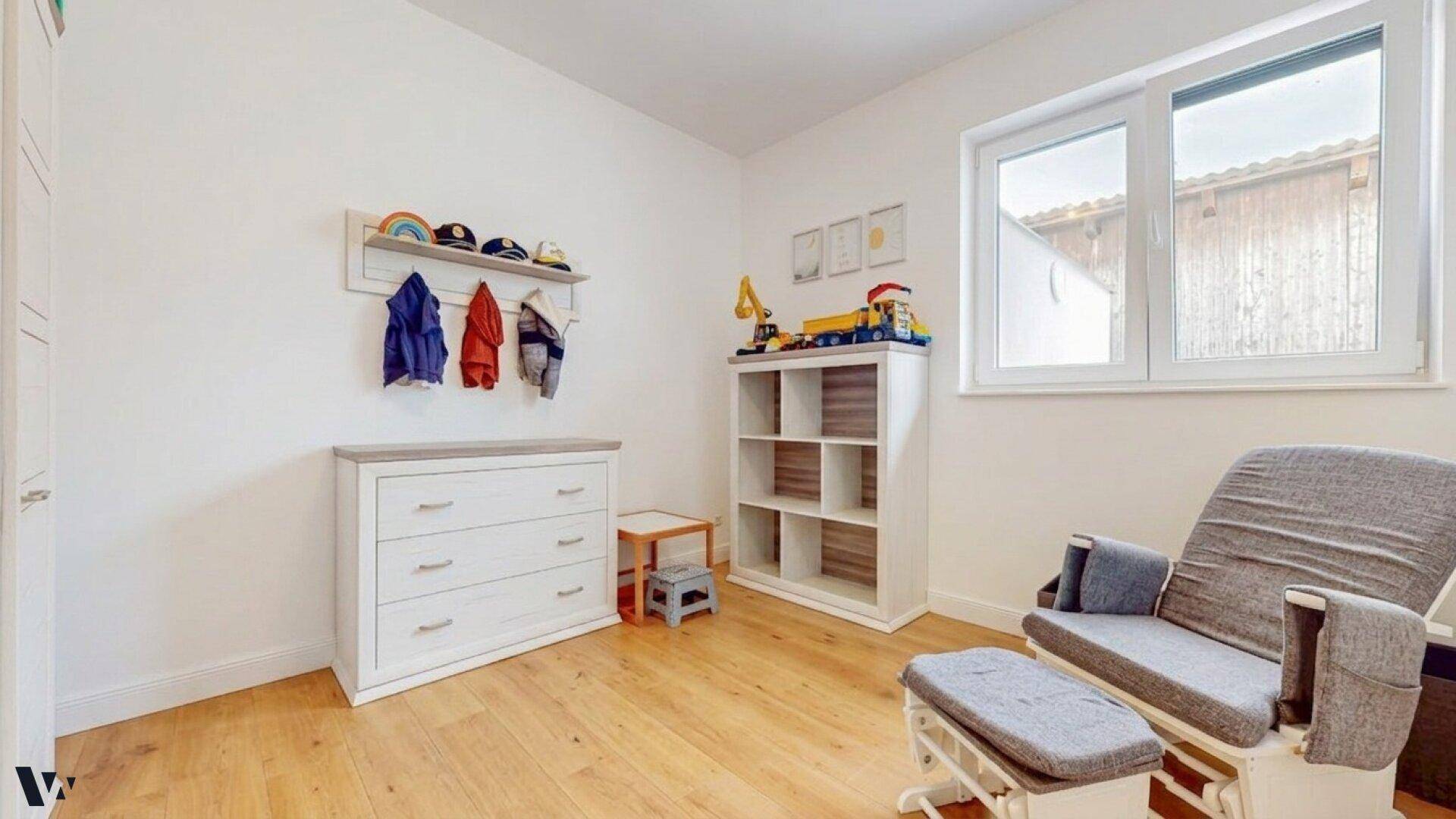 Kinderzimmer mit Wickelkommode, Regal und Schaukelstuhl, ideal für die Kleinsten.