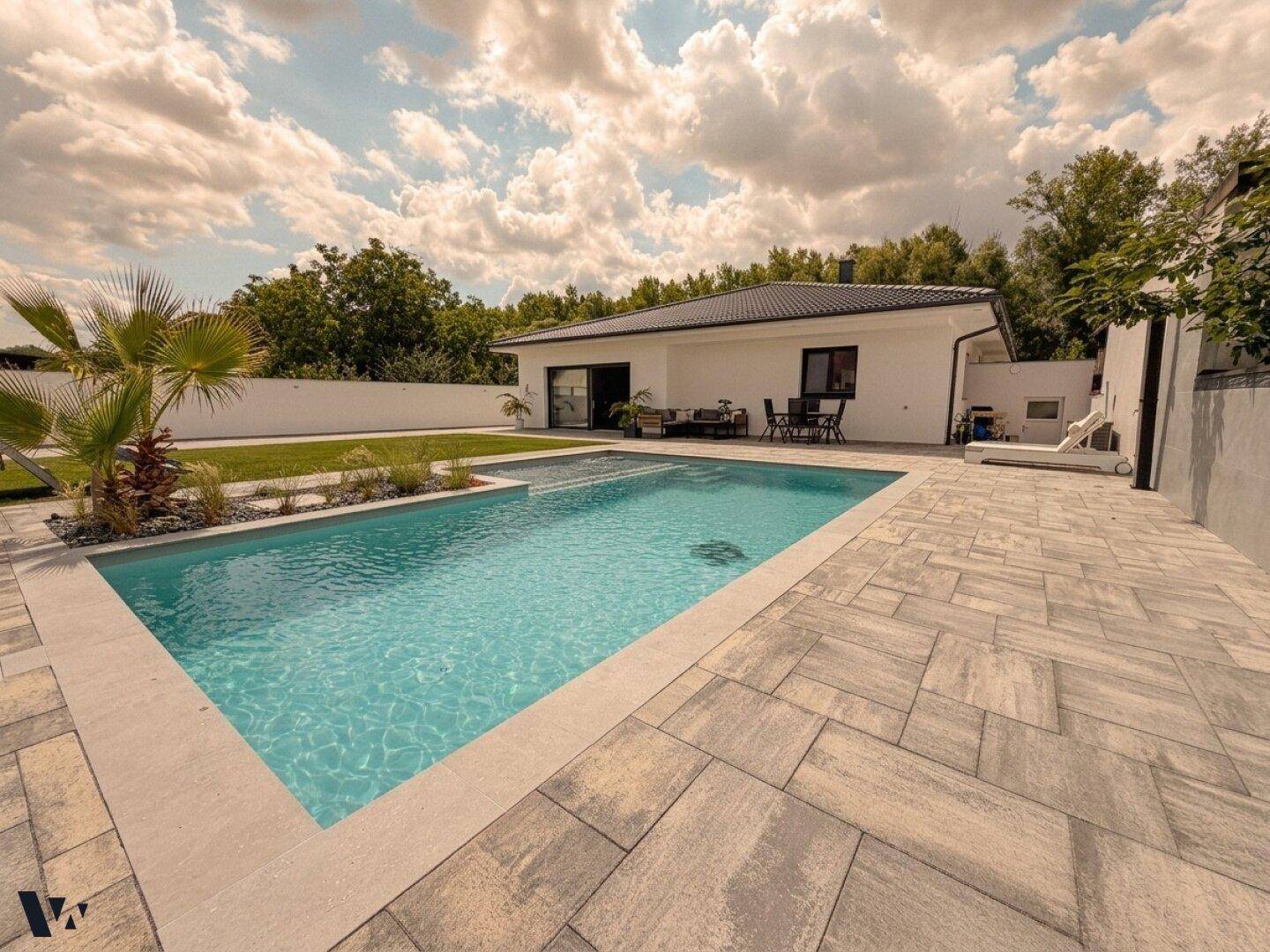 Moderner Poolbereich mit großzügiger Pflasterung und Blick auf das Einfamilienhaus.