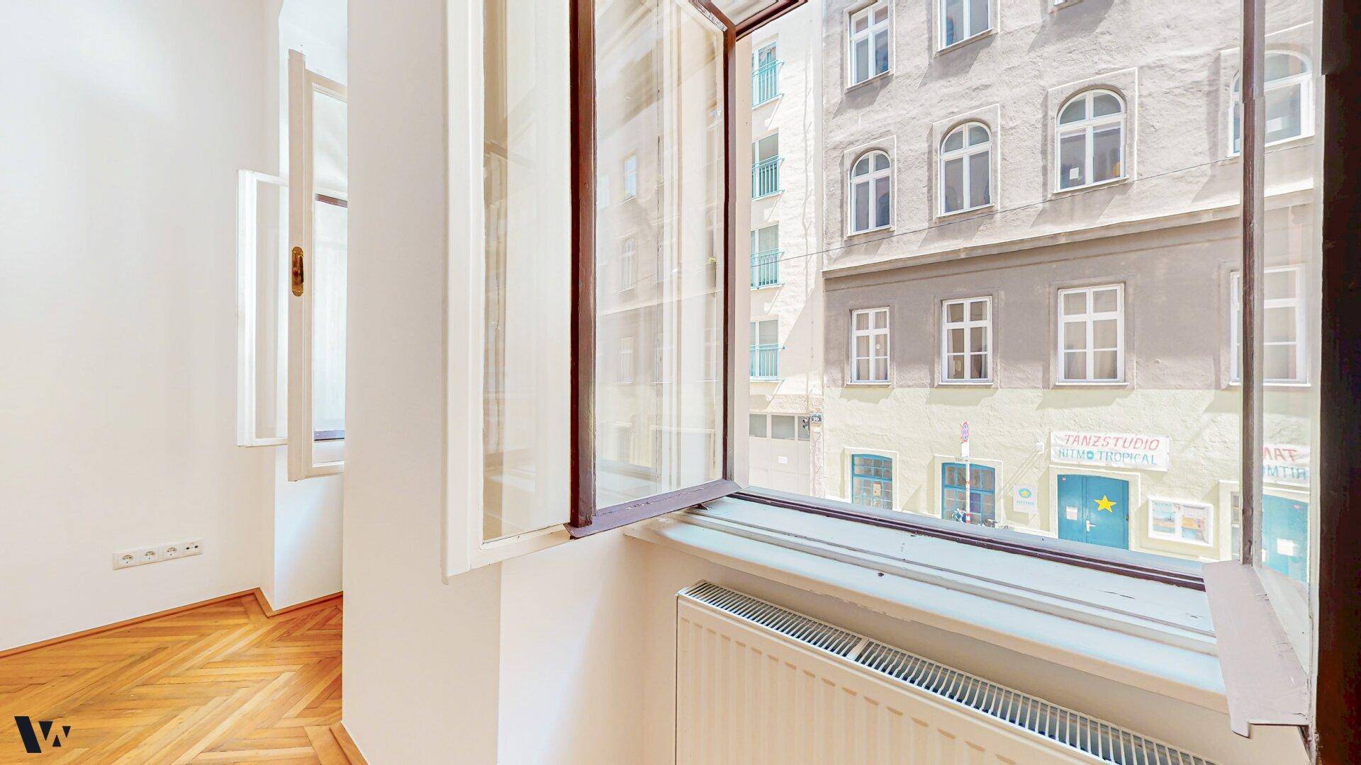 Blick aus dem Fenster auf die gegenüberliegende historische Fassade und die Straße.
