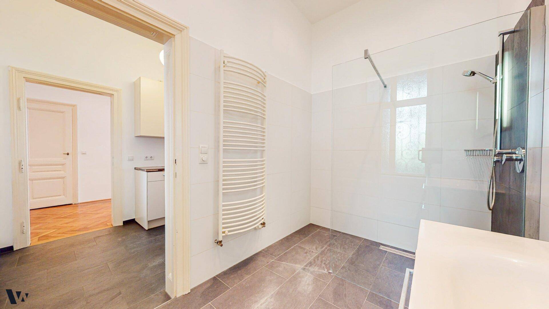 Modernes Badezimmer mit ebenerdiger Dusche, Handtuchheizkörper und Fliesenboden.